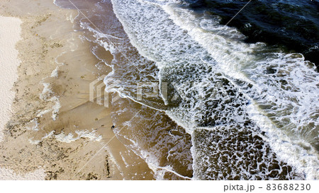 Aerial drone view flight over sea waves that roll onto sandy shore. Aerial drone view flight over sea waves that roll onto sandy shore. 83688230