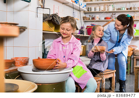 Schoolgirls learning from teacher to make ceramics 83689477
