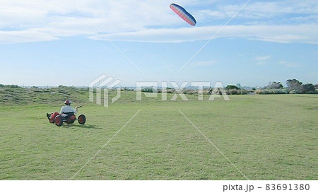 青空高く舞う凧に曳かれ、地上の小さなカートが進む海辺の公園より 青空高く舞う凧に曳かれ、地上の小さなカートが進む海辺の公園より 83691380