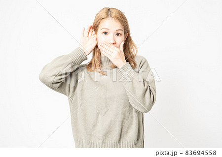 聞き耳を立てて噂を聞くセーターを着た若い女性 83694558