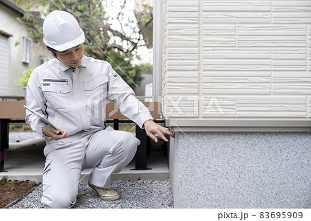 住宅の基礎部分を点検する作業服の男性 83695909