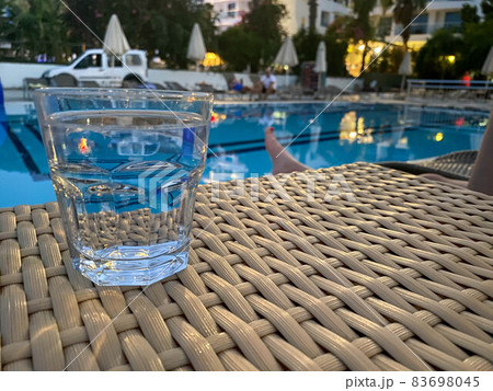 Glasses with tasty cocktail in front of a swimming pool with clear water. Close-up photo. Palm trees on the background. Vacation Glasses with tasty cocktail in front of a swimming pool with clear water. Close-up photo. Palm trees on the background. Vacation 83698045