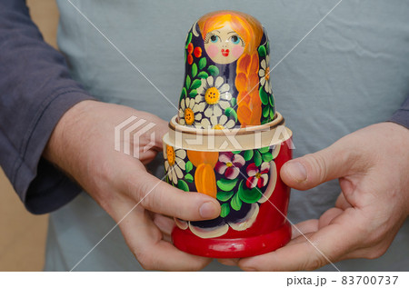 An adult male holding a wooden matryoshka doll. An uncovered tra An adult male holding a wooden matryoshka doll. An uncovered tra 83700737