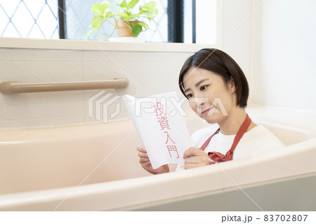 浴槽で投資の本を読んで考える女性 浴槽で投資の本を読んで考える女性 83702807