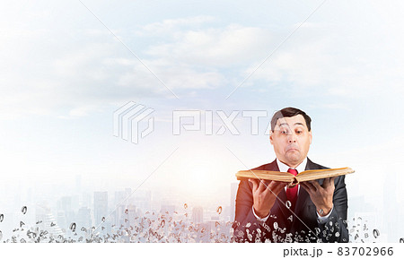 Surprised businessman holding open old book 83702966