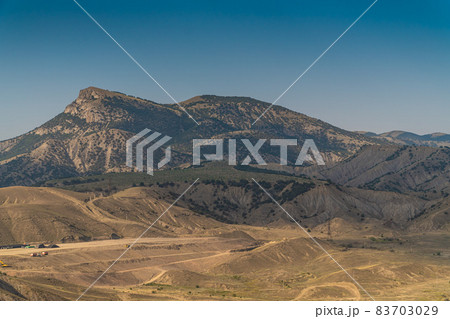 The Republic of Crimea. July 18, 2021. Picturesque landscape of the Crimean mountains near the city of Sudak in warm sunny weather. The Republic of Crimea. July 18, 2021. Picturesque landscape of the Crimean mountains near the city of Sudak in warm sunny weather. 83703029