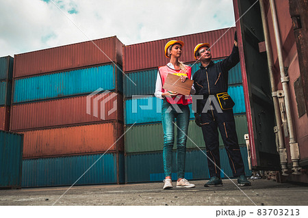 Industrial worker works with co-worker at overseas shipping container yard 83703213