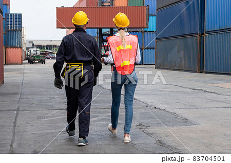 Industrial worker works with co-worker at overseas shipping container yard 83704501