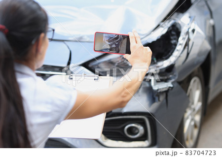 Woman insurance agent taking pictures of broken car on mobile phone closeup 83704723