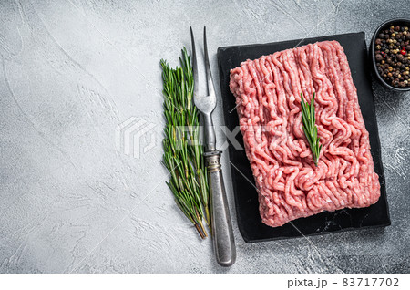 Minced chicken or turkey raw meat on cutting board with herbs. White background. Top View. Copy space 83717702