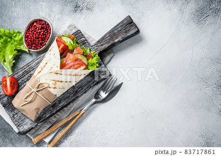 Wrap sandwich, roll with fish salmon and vegetables. White background. Top view. Copy space 83717861