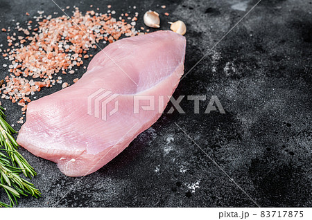 Raw Poultry turkey breast fillet meat on a butcher table with rosemary and salt. Black background. Top View. Copy space 83717875