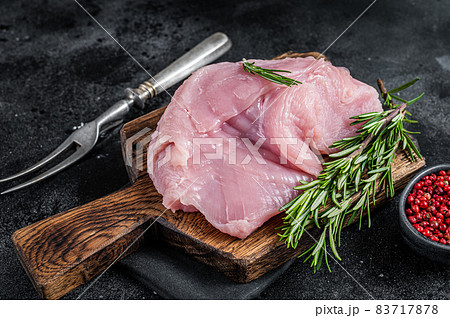 Fresh Raw whole big turkey breast fillet on wooden board. Black background. Top View Fresh Raw whole big turkey breast fillet on wooden board. Black background. Top View 83717878