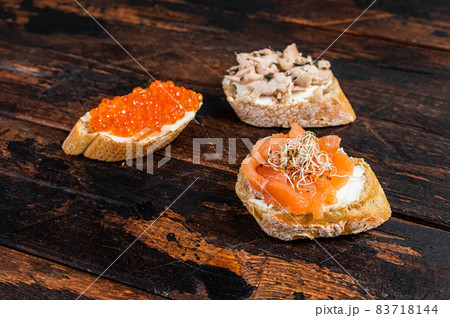 Bruschetta with Hot Smoked salmon, red caviar and herbs. Wooden background. Top view 83718144