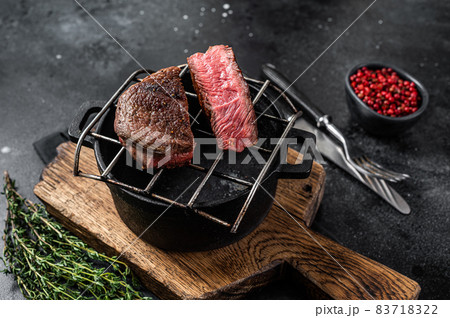 Beef tenderloin steak is grilled on a grill pan. Black background. Top view 83718322
