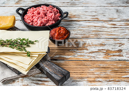 Lasagne raw sheets and other ingredients. White wooden background. Top view. Copy space 83718324