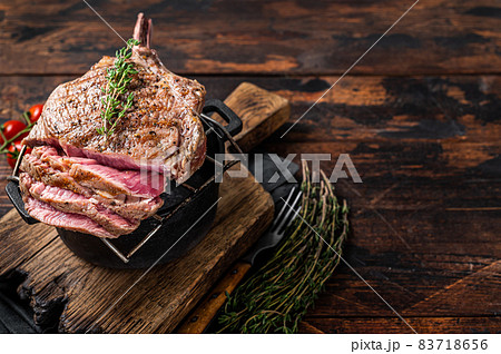 Grilled Tomahawk rib eye steak on grill with herbs. Wooden background. Top view. Copy space 83718656