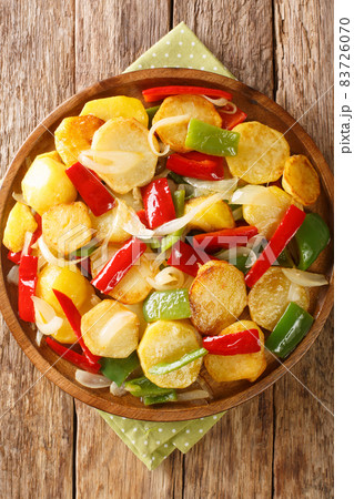 Fried potatoes with onions and red and green peppers close-up in a plate. vertical top view Fried potatoes with onions and red and green peppers close-up in a plate. vertical top view 83726070