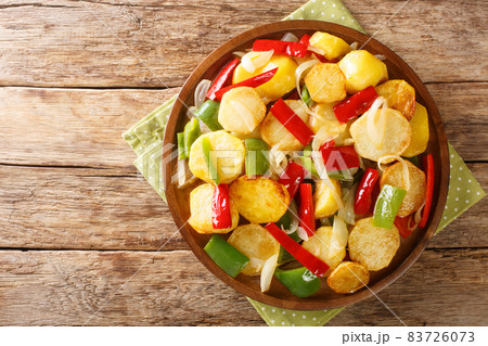 Patatas a lo pobre is a simple potato dish from Andalusian cuisine made of sliced potatoes are fried in olive oil with onion and peppers close up on the table. Horizontal top view 83726073