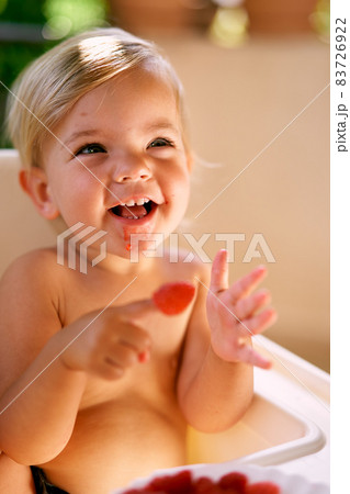 Smiling child with stained chin holding raspberry on his finger Smiling child with stained chin holding raspberry on his finger 83726922