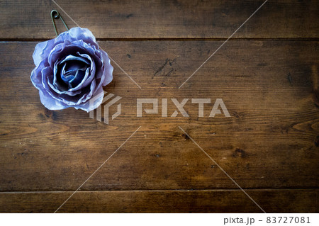 青紫のバラのコサージュとアンティークビンテージ調のレトロな茶色で木目のテーブル 83727081