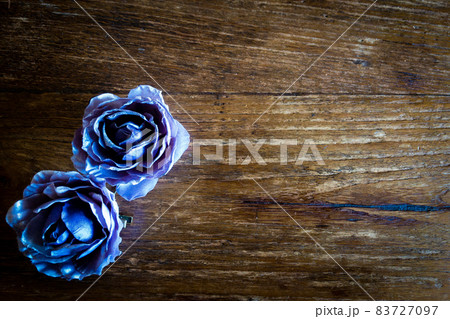 青紫のバラのコサージュとアンティークビンテージ調のレトロな茶色で木目のテーブル 83727097