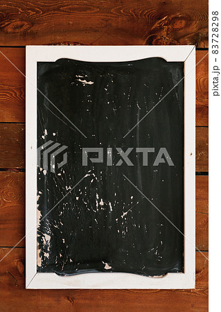 Black painting in a white frame lies on a lacquered brown wooden surface Black painting in a white frame lies on a lacquered brown wooden surface 83728298