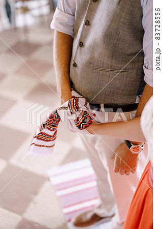 Groom and bride stand with a tied towel on their hands 83728556