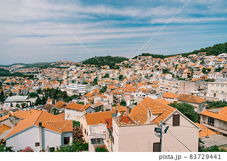 Orange roofs of old houses in Sibenik against a background of blue sky and greenery Orange roofs of old houses in Sibenik against a background of blue sky and greenery 83729441