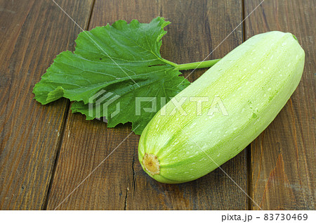 Fresh white zucchini zucchini with green leaf lies on wooden surface. Studio Photo 83730469