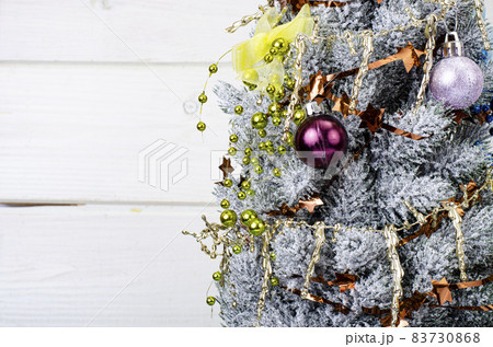 We celebrate Christmas and New Year. Small decorative Christmas tree decorated with balls and toys. Studio Photo. 83730868