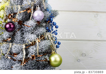 We celebrate Christmas and New Year. Small decorative Christmas tree decorated with balls and toys. Studio Photo. 83730869