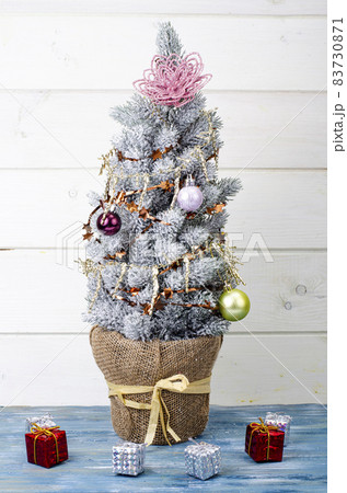 We celebrate Christmas and New Year. Small decorative Christmas tree decorated with balls and toys. Studio Photo. 83730871