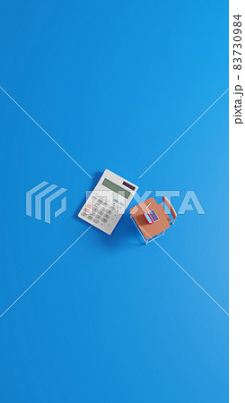 平面上に置かれたミニチュアのスクールデスクと電卓 83730984