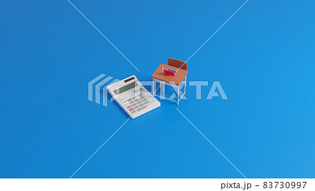 平面上に置かれたミニチュアのスクールデスクと電卓 83730997