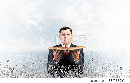 Surprised businessman holding open old book 83733204