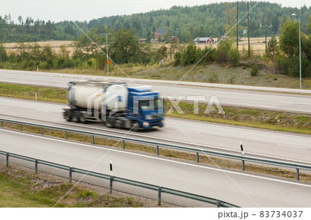 Blurred cargo car in motion. Asphalt roads with car at autumn in Finland. Blurred cargo car in motion. Asphalt roads with car at autumn in Finland. 83734037