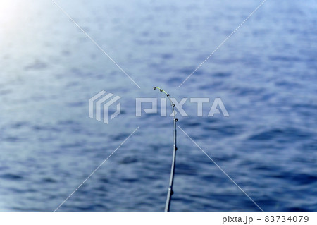 Fishing rod on a background of blue water, selective focus with copy space for text. Fishing rod on a background of blue water, selective focus with copy space for text. 83734079