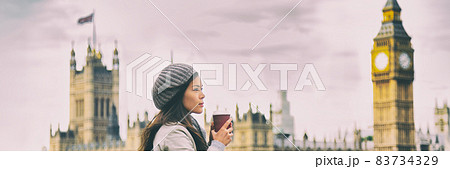 London travel woman drinking coffee cup by Big Ben Westminster in cold morning fall. Asian tourist girl pensive looking at view banner panorama. 83734329