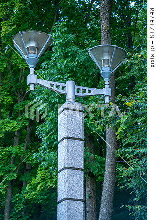 Street lamp in the park against the background of green trees, modern street lamp, expensive marble street lamp Street lamp in the park against the background of green trees, modern street lamp, expensive marble street lamp 83734748