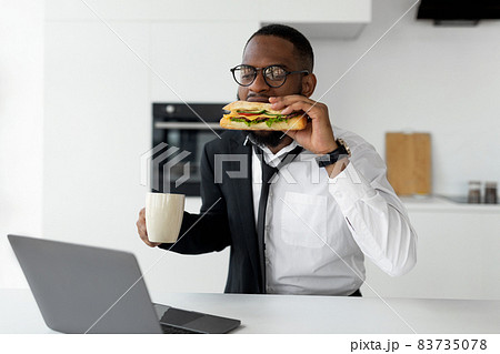 Black man rushing to work eating sandwich at home 83735078