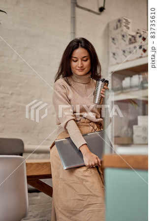 Young female with laptop and hot drink 83735610