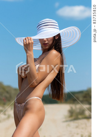 Topless woman covering breast on beach 83735810