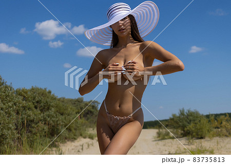 Topless woman covering breast on beach 83735813