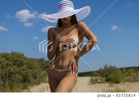 Topless woman covering breast on beach 83735814