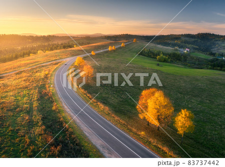 Aerial view of winding road in autumn forest at sunset Aerial view of winding road in autumn forest at sunset 83737442