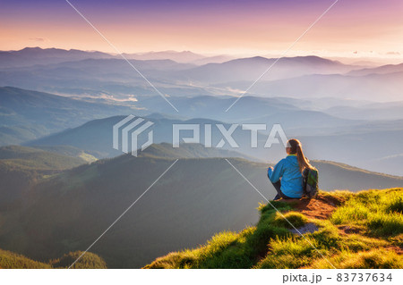 Young woman with backpack sitting on the mountain peak 83737634