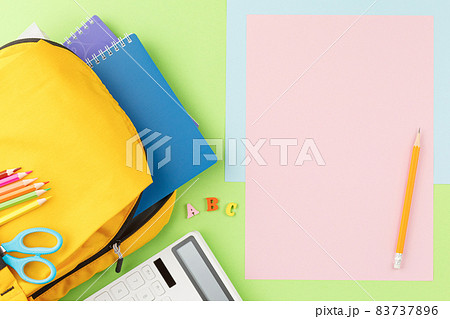 Yellow backpack with notebooks and study supplies. 83737896