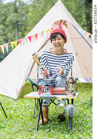 キャンプ場でホットケーキを焼く若い女性 83738634
