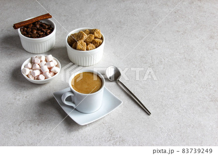 Vanilla coffee with brown sugar and marshmallow. Tasty steam espresso in a cup with coffee beans. Vanilla coffee with brown sugar and marshmallow. Tasty steam espresso in a cup with coffee beans. 83739249